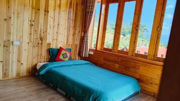 Una habitación con paneles de madera, una cama, un ventanal y vistas a follaje.
