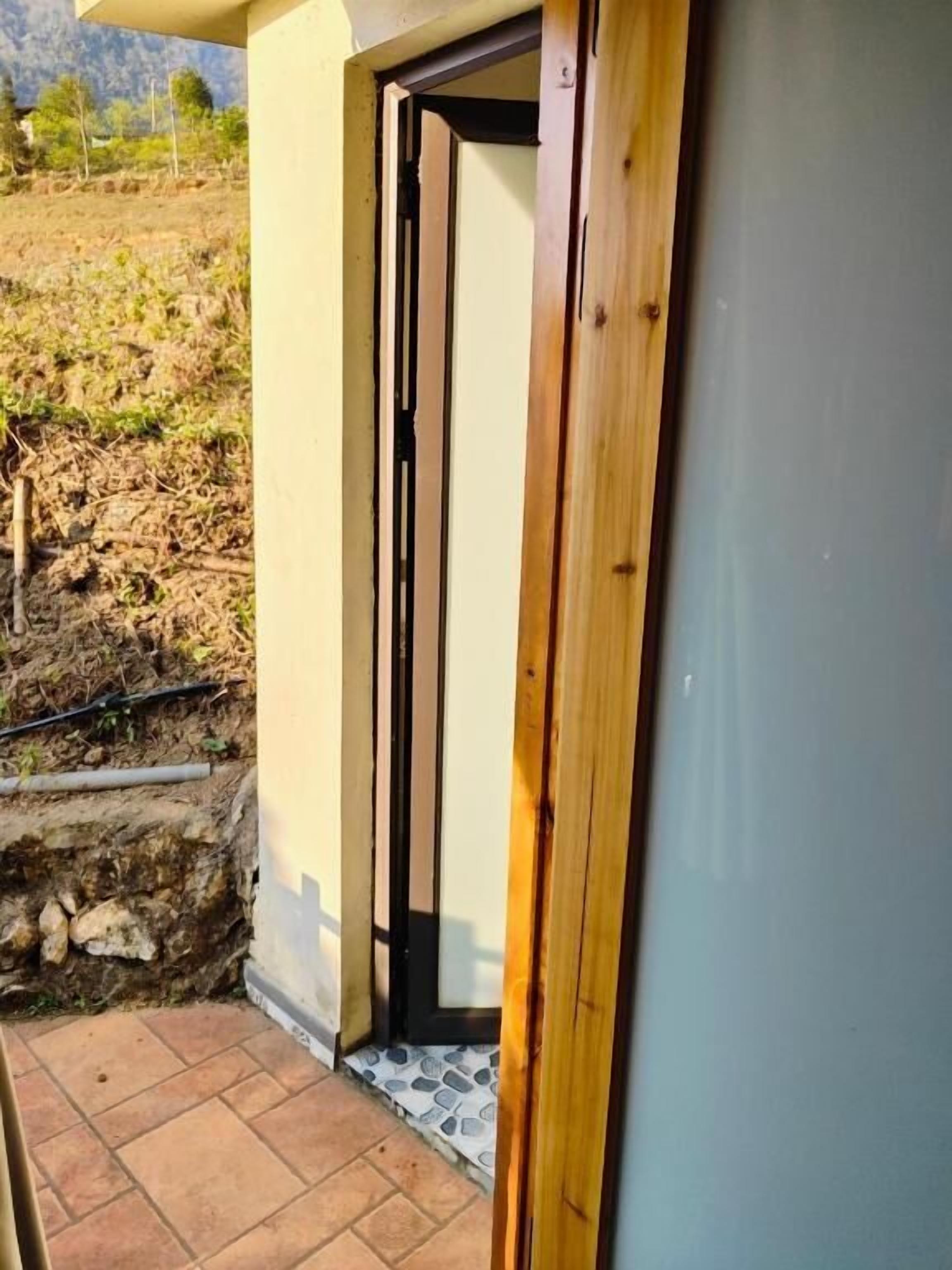 A doorway leading to a room with a view of a landscaped area and a stone wall.