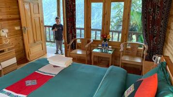 A wooden cabin with a bed, a table with chairs, and a window with curtains.