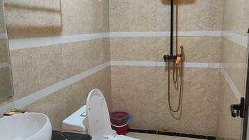 A bathroom with a toilet, sink, shower, and a towel rack.