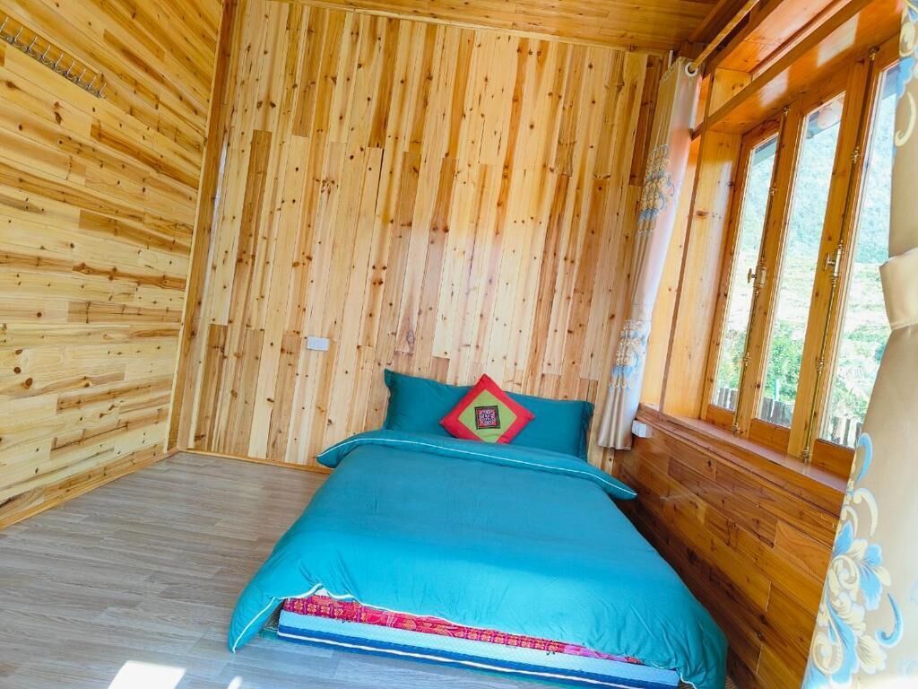 Una habitación de cabaña de madera con una cama, paredes de madera y una ventana.