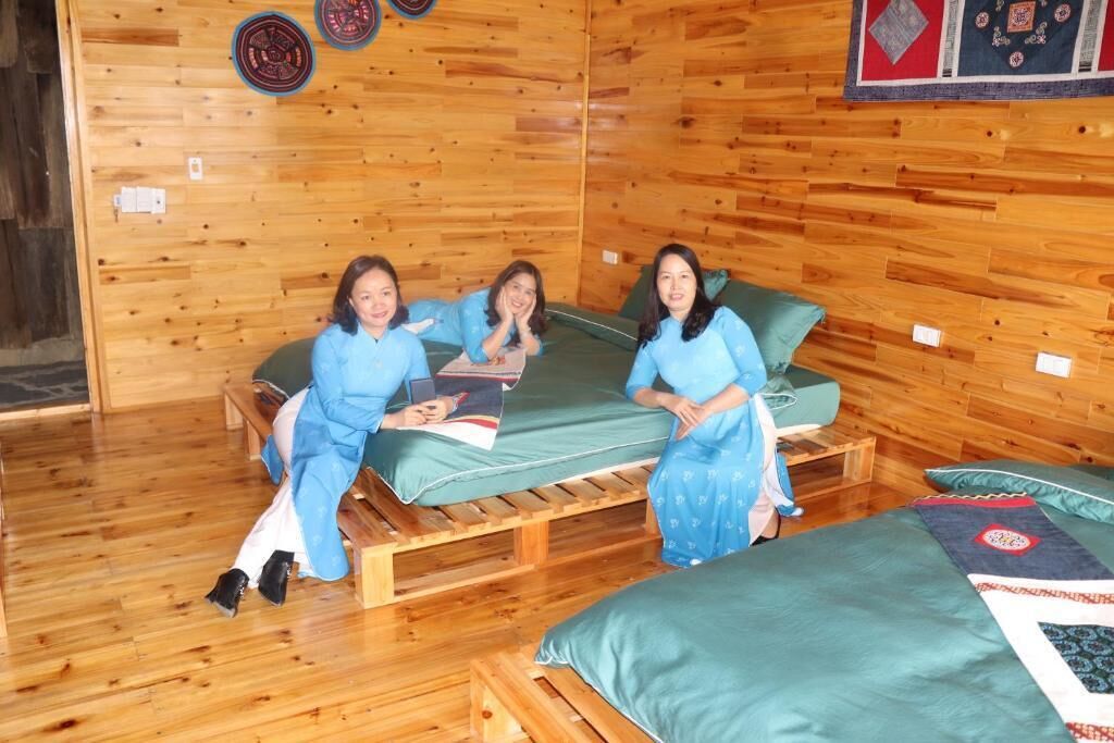 A wooden cabin-style room with three beds, a wooden floor, and a wall with decorative plates.