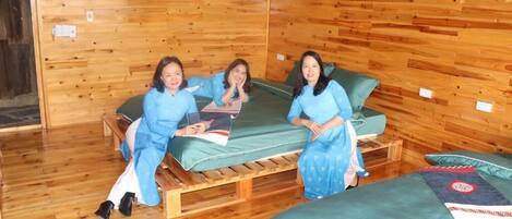 A wooden cabin-style room with three beds, a wooden floor, and a wall with decorative plates.