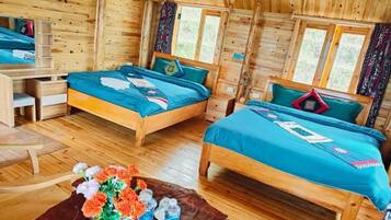 Eine Holzhütte mit zwei Betten, einem Schreibtisch und einem Couchtisch mit Blumen und Wasserflaschen.