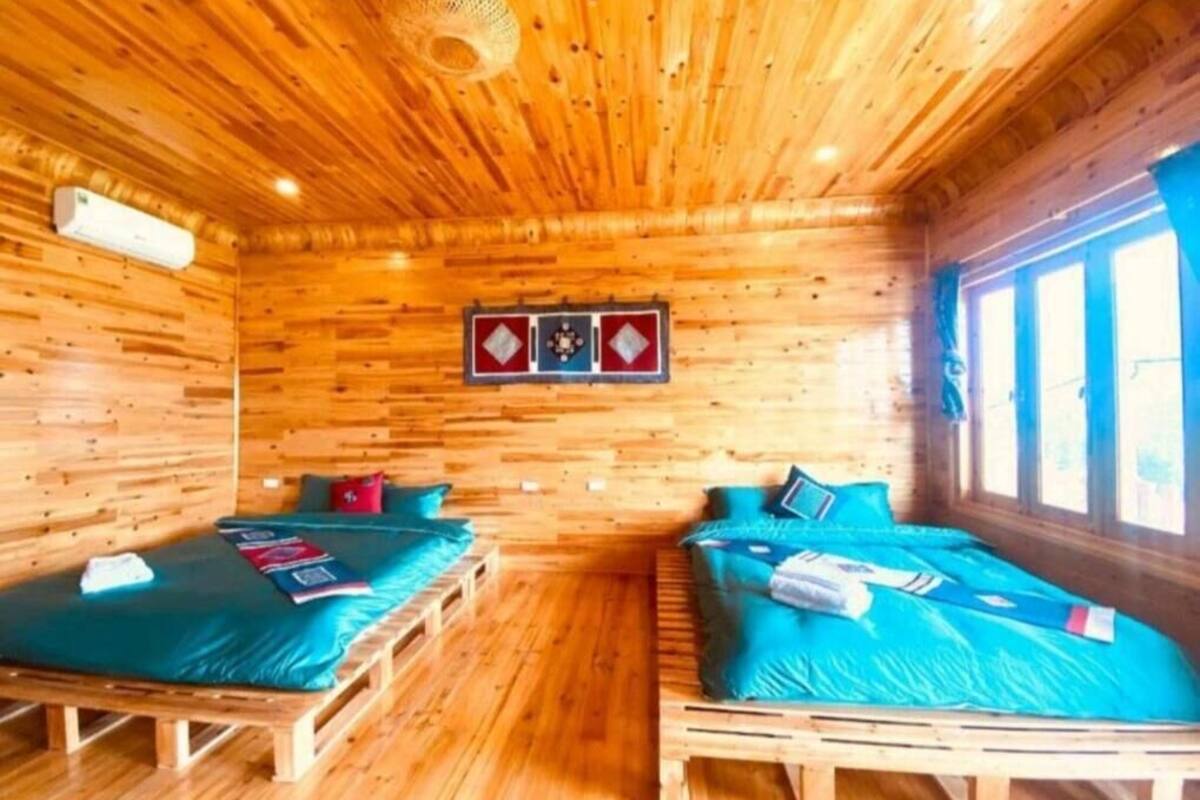 A cabin with two wooden beds, a woven ceiling light, and a wall-mounted picture.
