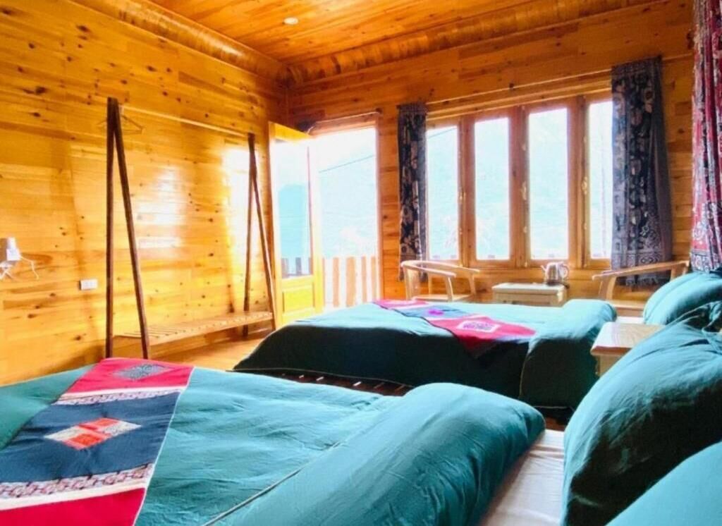 A wooden cabin with two beds, a bench, and a window with curtains.