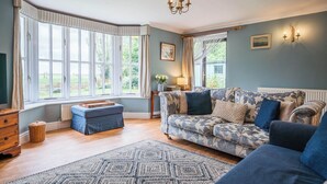 Un salon avec un canapé, un pouf et un tapis à motifs.