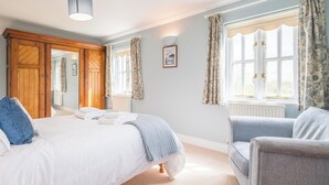 Une chambre à coucher avec un lit, une chaise, une armoire et une fenêtre avec des rideaux.
