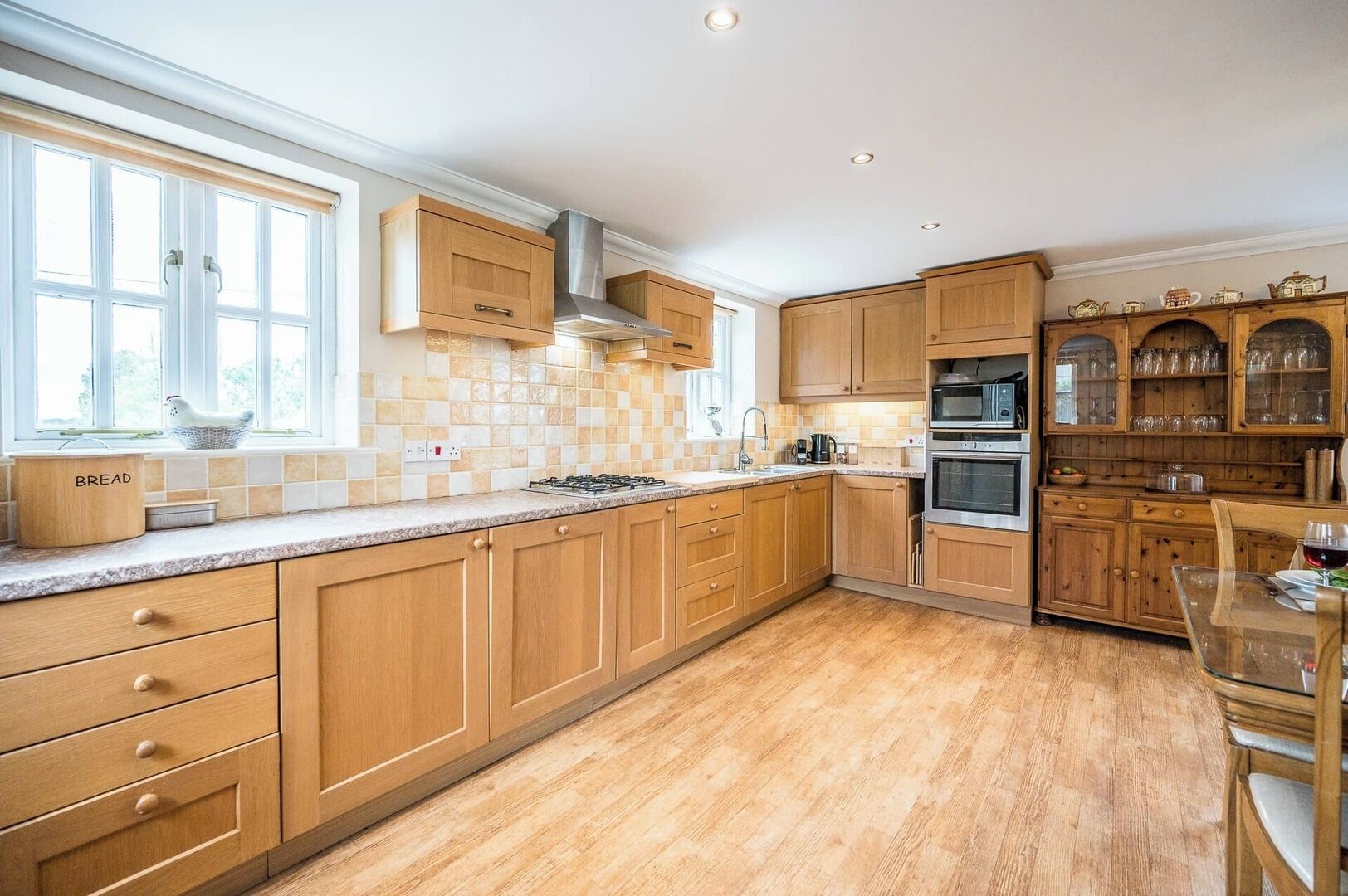 A kitchen with wooden cabinets, a gas stove, and a dining area with a glass table.