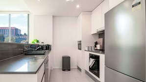 Een moderne keuken met een roestvrijstalen koelkast, een inbouwoven en een raam met uitzicht op een stadsgezicht.