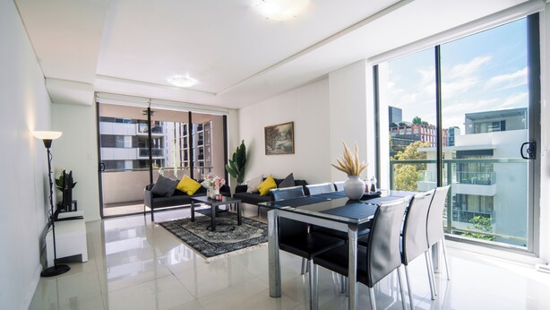 Een moderne woonkamer met een eethoek, grote ramen en uitzicht op de stad.