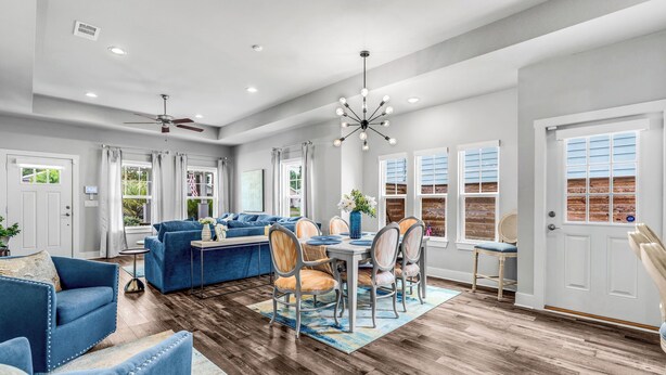 A spacious living room with a dining area, a ceiling fan, and a modern chandelier. - 3-bedroom house with fenced yard and private pool (Pensacola)