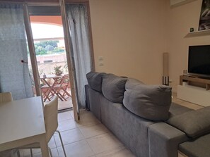 Un soggiorno con un divano grigio, una televisione e una zona pranzo con tavolo e sedie.
