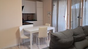 Un espacio habitable compacto con kitchenette, una mesa de comedor y un sofá.