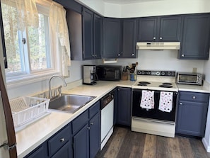 A compact kitchen with dark cabinets, a microwave, a toaster, and a dishwasher.