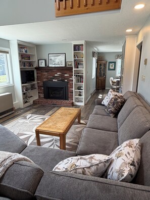 A living room with a fireplace, a sofa, a coffee table, and a bookshelf.