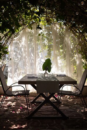 A table set for two under a canopy with a hanging light fixture and a potted plant. - A unique stay steps from the beach with breakfast included (Rincón)