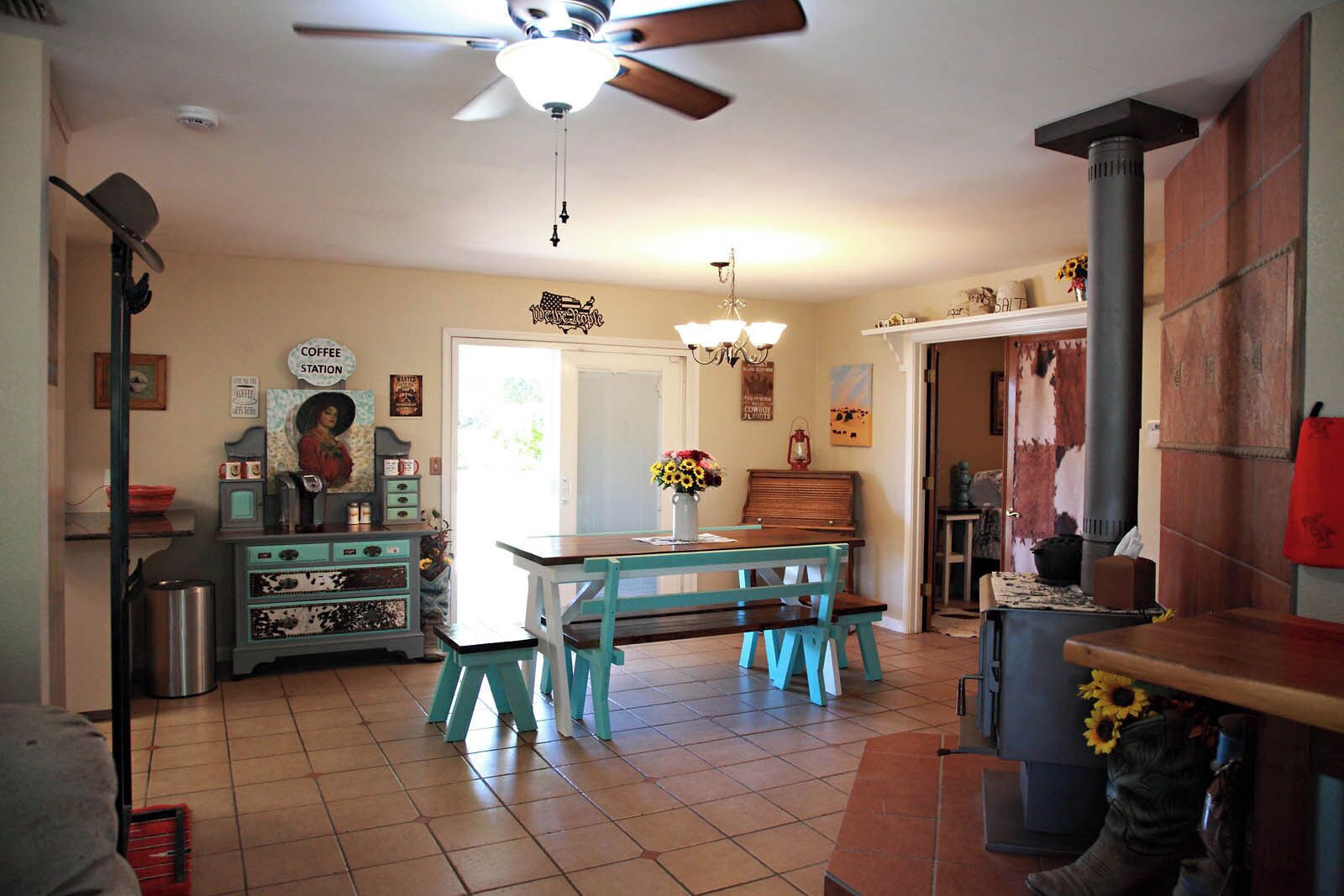A kitchen with a coffee station, a dining table with chairs, a ceiling fan, and a fireplace.