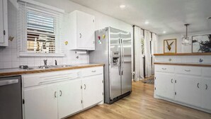 Eine Küche mit weißen Schränken, einem Edelstahl-Kühlschrank und einer Holz Arbeitsplatte.