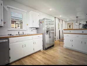 Eine Küche mit weißen Schränken, einem Edelstahl-Kühlschrank und einer Holz Arbeitsplatte.