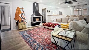 Ein Wohnzimmer mit Kamin, einer Couch, einem Couchtisch und einem gemusterten Teppich.