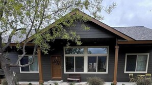 A single-story house with a front porch, a door, and a bench. - McCall Basecamp (Donnelly)