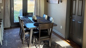 A dining area with a table set for four, a chandelier, and a door with a picture above it. - McCall Basecamp (Donnelly)