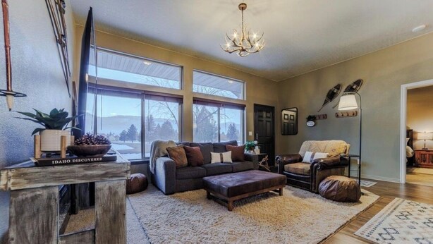 A living room with a sofa, ottoman, and a large window. - McCall Basecamp (Donnelly)