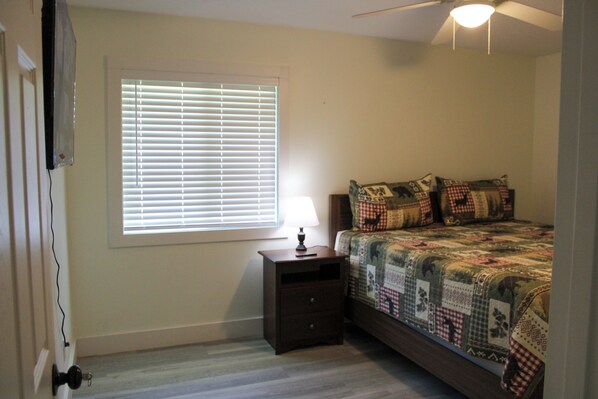 A bedroom with a bed, a nightstand, a window with blinds, and a ceiling fan. - 3BR Home - Prime Pigeon Forge Location - Near Dining & Shops!! (Pigeon Forge)