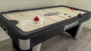 Una mesa de hockey sobre hielo Brunswick con un ventanal encima.