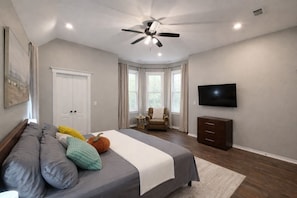 A bedroom with a bed, a ceiling fan, a TV, a chair, and a window. - 1-Story Ranch -- Fishing --Two Kings -- 85" TV -- 4Bedroom (Mount Pleasant)