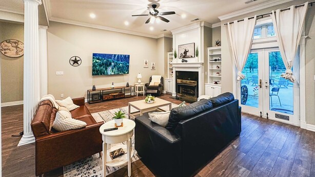 A living room with a fireplace, a television, and a view of the outdoors. -  11-Acre fenced 3500 SqFt Ranch on I-30, 2 King Suites, 1 Story. 10 Beds. Pond. (Mount Pleasant)