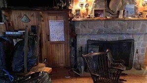 Ein gemütliches Zimmer mit Kamin aus Stein, Holzmöbeln und einem Kalender an der Wand.