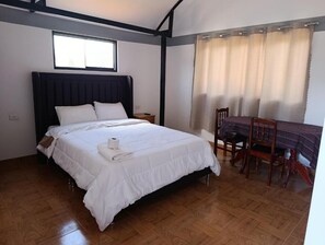 Quarto com cama, janela, mesa e cadeiras, e cortina.
