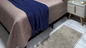 Un dormitorio con una cama, una mesita de noche, aire acondicionado de pared y una ventana con cortinas.