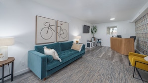 Una sala de estar moderna con un sofá azul verdoso, un mostrador de recepción de madera y una pared con estampado.