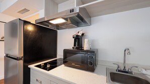 Una cocina compacta equipada con refrigerador, microondas y lavamanos.