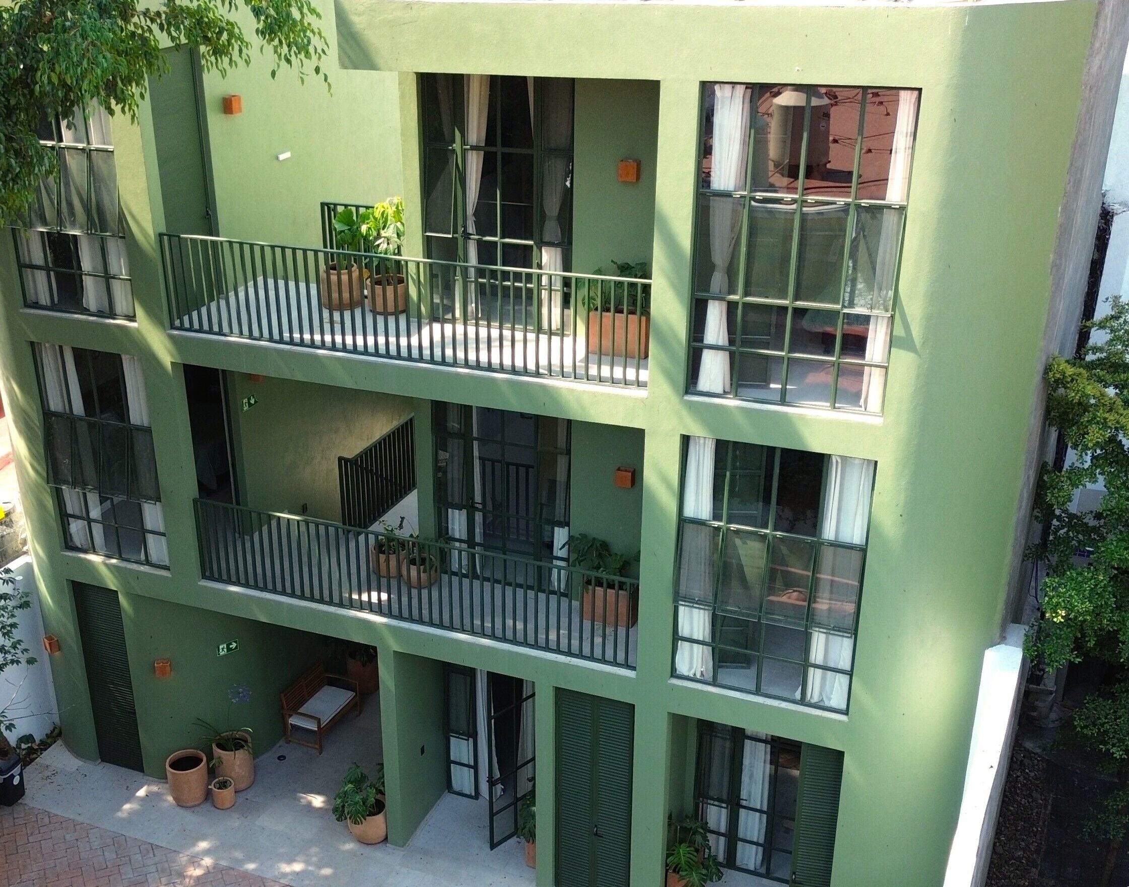A multi-story building with balconies, potted plants, and a flat roof.