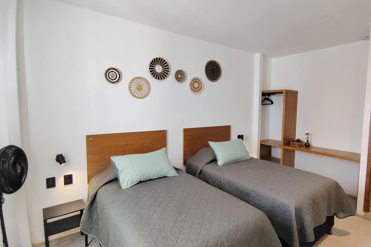Un dormitorio con dos camas, una mesita de noche, un espejo y adornos en la pared.