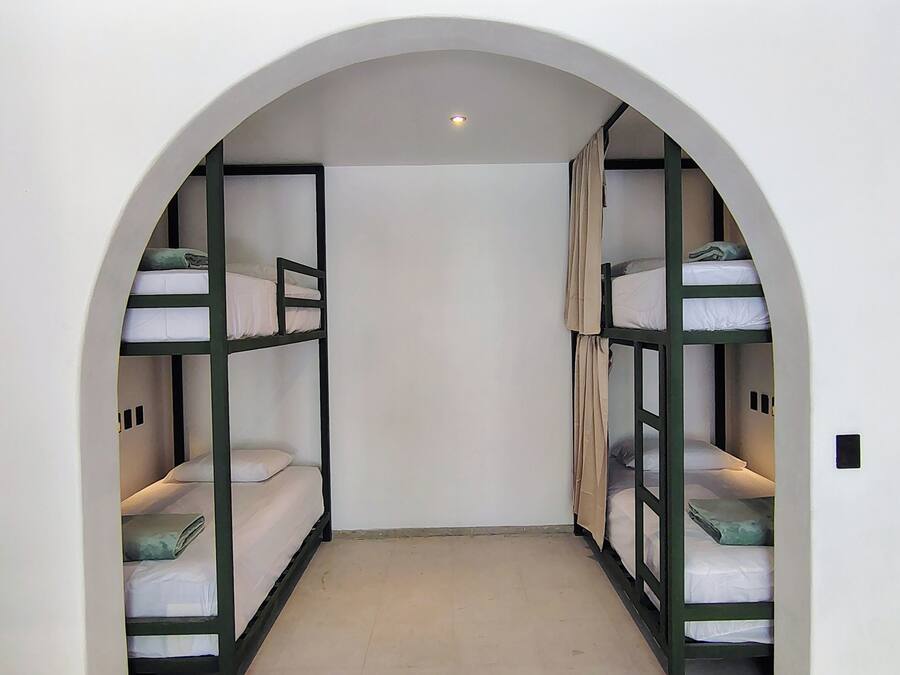 A narrow hallway with bunk beds on either side, an arched ceiling, and a recessed light at the end.
