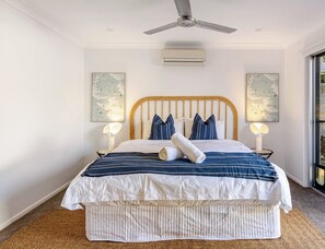 Ein Schlafzimmer mit Bett, Deckenventilator, Wandklimaanlage und zwei Wandbildern.