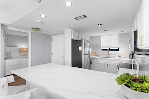 Una cocina moderna con armarios blancos, encimera de mármol y electrodomésticos de acero inoxidable.