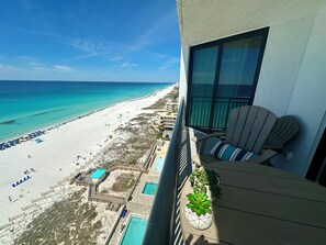 Ein Balkon mit Blick auf einen Strand, einen Pool und einen Stuhl.