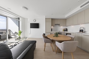 A modern kitchen with a dining area, a flat-screen TV, and a large window.