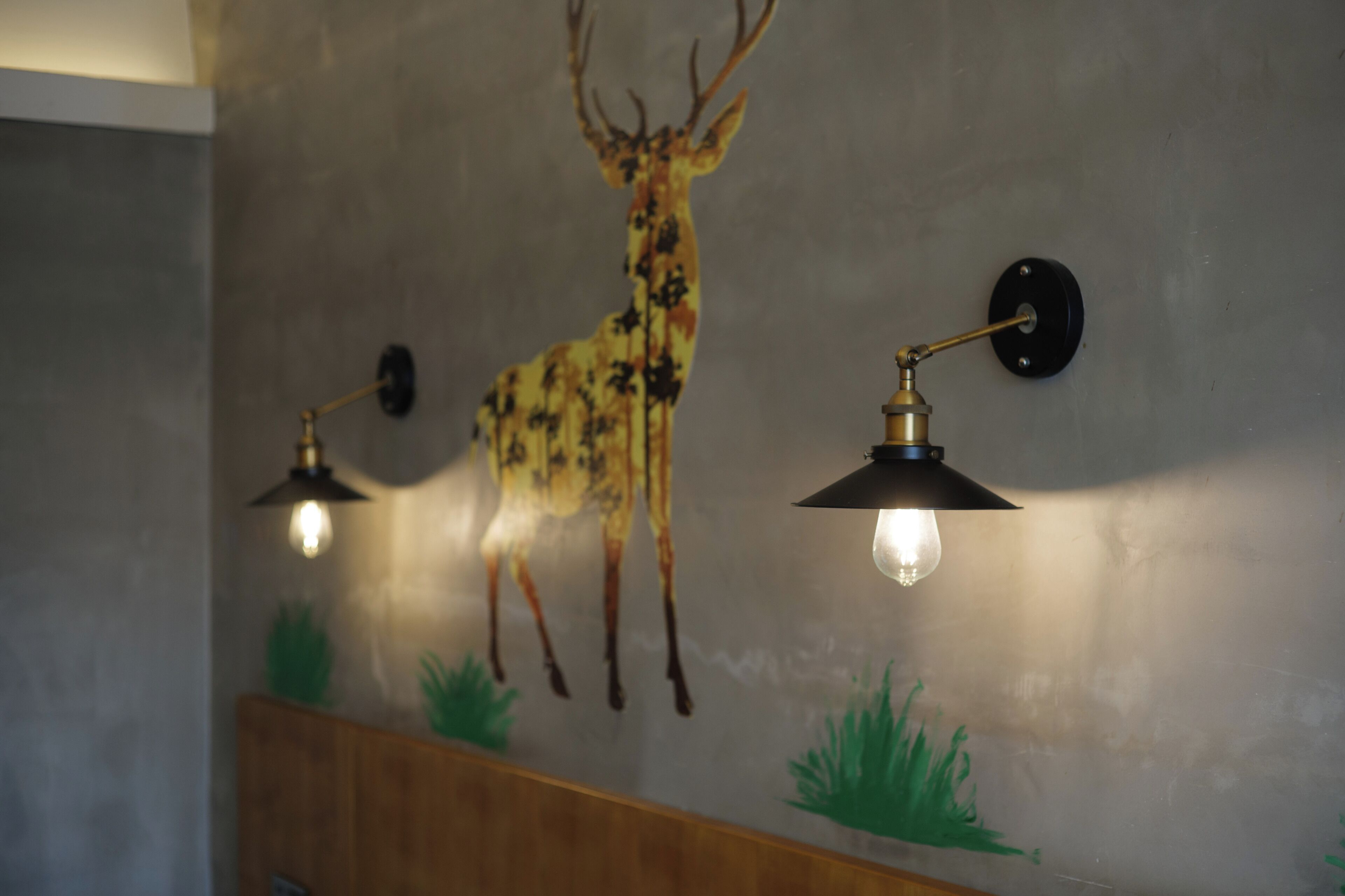 A wall with a deer mural and two wall-mounted lights.