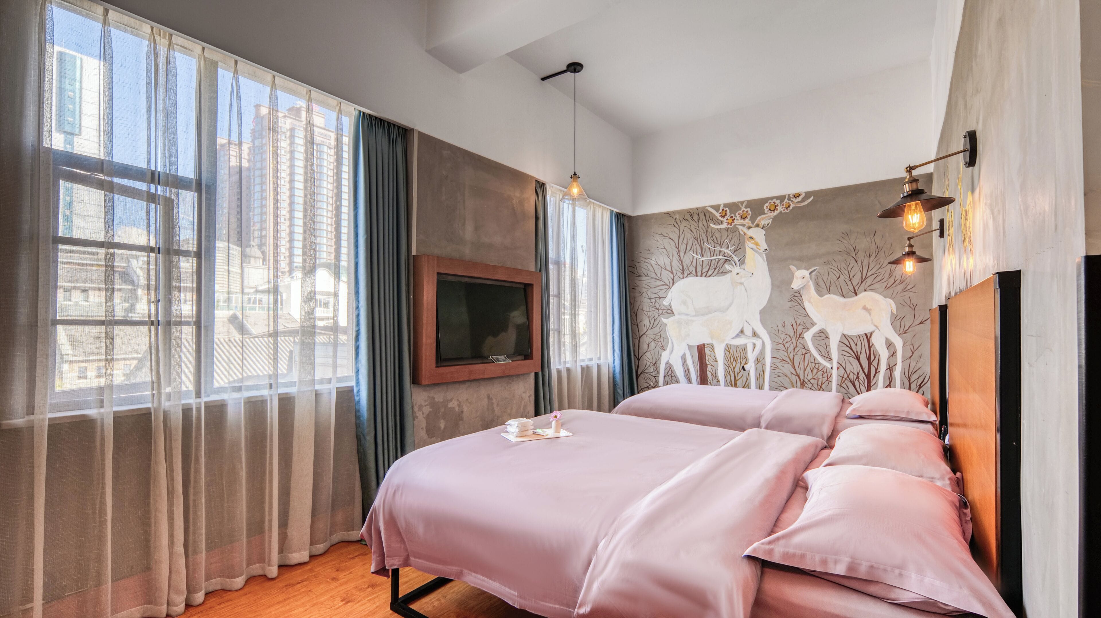 A bedroom with two beds, a TV, and a mural of deer.