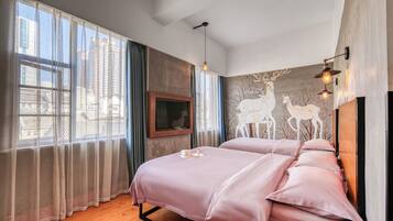 A bedroom with two beds, a TV, and a mural of deer.