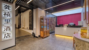 A hotel lobby with a reception desk, a wooden cabinet, and a sign with Chinese characters. - Gongxili - Chujian Hotel (Kunming)