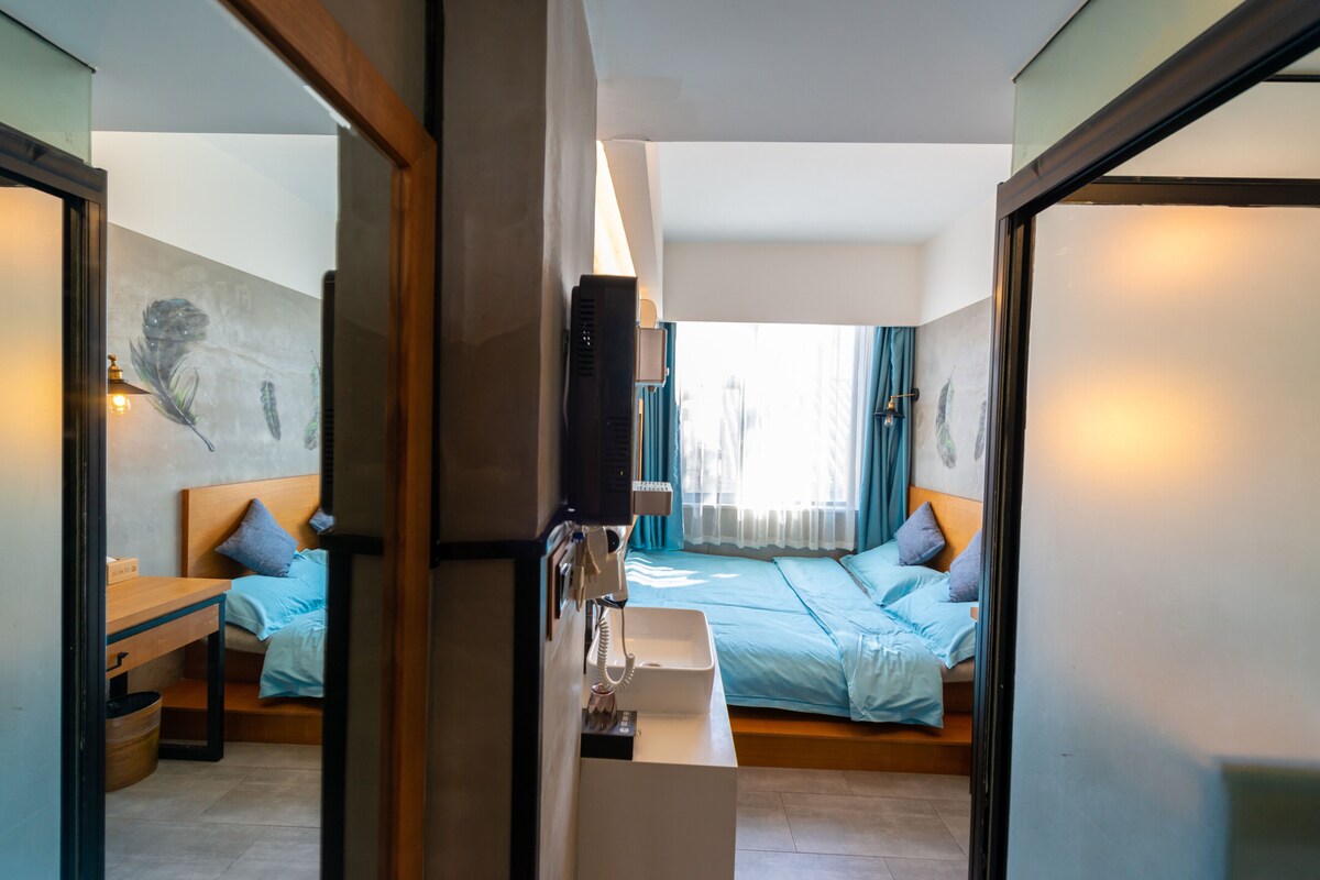 Habitación de hotel con cama, mesita de noche y un espejo grande que refleja la habitación.