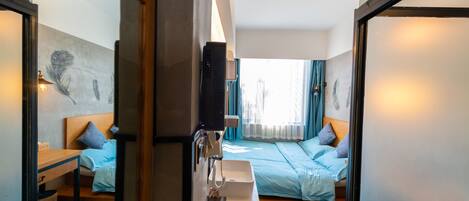 A hotel room with a bed, bedside table, and a large mirror reflecting the room.